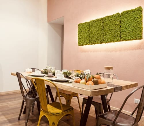 Zona pranzo moderna dell'Apartment Todo Sicily a Catania con tavolo in legno, sedie gialle, parete con muschio verde e rosa
