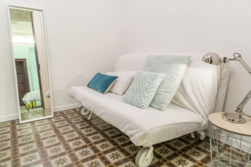 Camera moderna di B&B a Catania con divano bianco, cuscini decorativi, piastrelle a motivi, specchio e lampada da tavolo