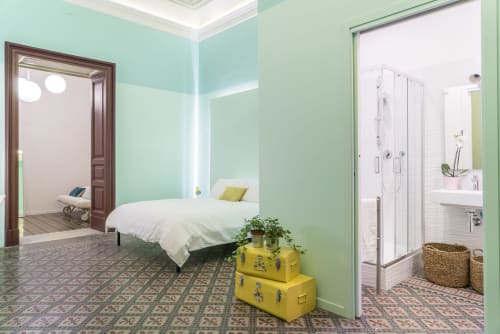 Camera da letto verde menta brillante con letto bianco, valigie gialle vintage e ingresso moderno del bagno presso Todo Sicily B&B