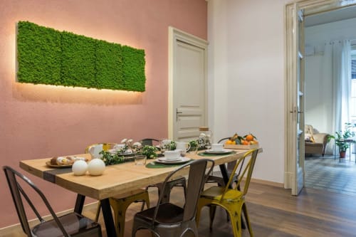 Moderna zona pranzo dell'Apartment Todo Sicily con tavolo in legno, parete verde con arte muschio e accento rosa a Catania