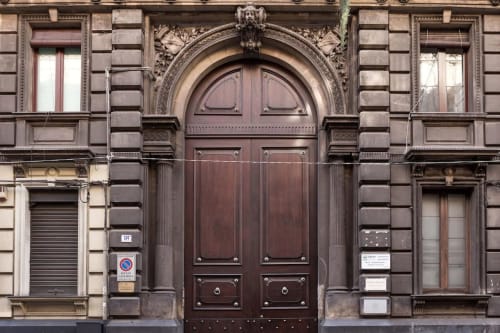 Affascinante facciata storica di edificio catanese con porta in legno ad arco e dettagliati lavori in pietra, alloggio B&B in Sicilia