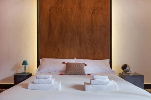 Lussuosa camera da letto della suite Fire di Todo Sicily con testata in legno, biancheria bianca, cuscini decorativi e illuminazione ambient