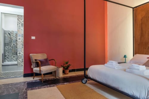Camera moderna al Todo Sicily B&B di Catania con muri rossi, letto matrimoniale, poltrona e bagno privato