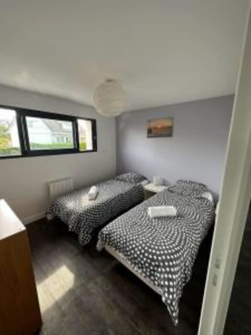 Chambre lumineuse avec lits jumeaux et literie à motifs à L'Écrin du Blanc Caillou, Saint Pair sur Mer