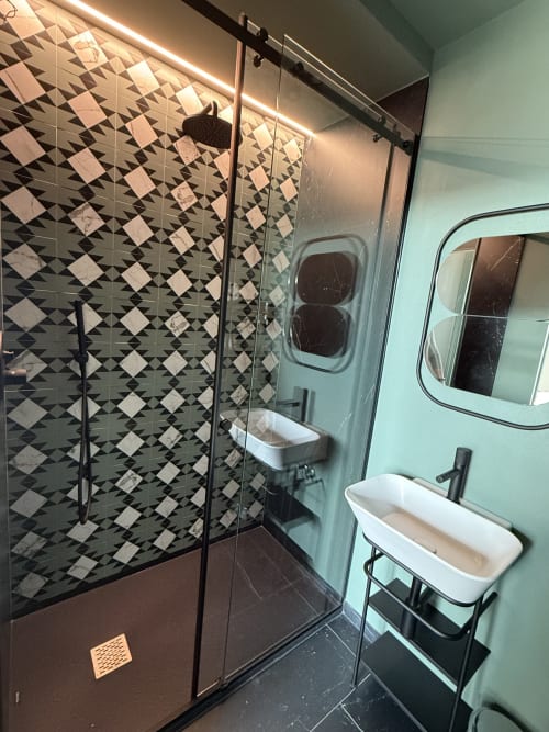 Moderno bagno a Volta 70 Napoli con doccia a piastrelle geometriche bianco e nero, doppi lavabi e pareti verde menta