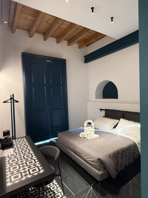 Camera Deluxe Doppia Volta 70 Napoli con vista sulla città, letto moderno, travi in legno a vista, guardaroba scuro e linee geometriche