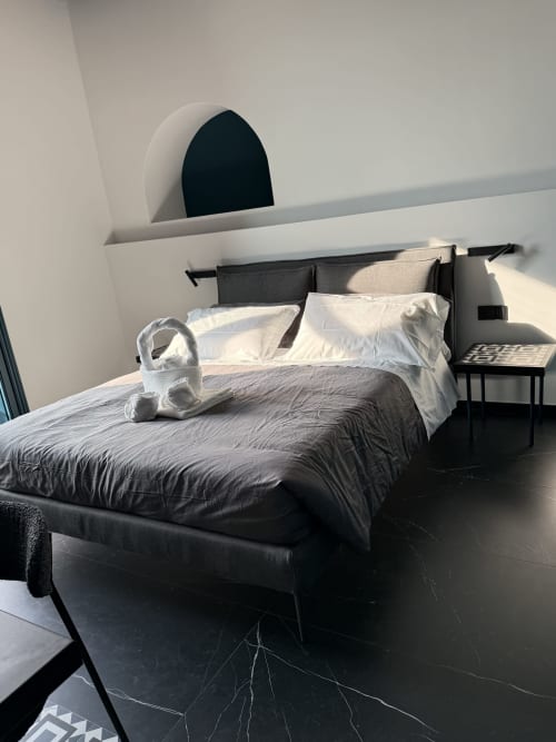Camera Deluxe Doppia moderna a Volta 70 Napoli con letto scuro, cuscini bianchi, vista città e design minimalista