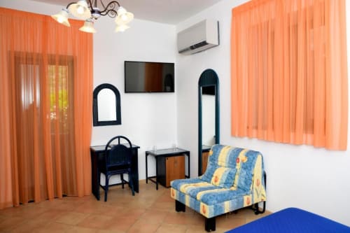 Accessible double room at Hotel Principe di Rinella with orange curtains, TV, comfortable seating, and modern amenities in