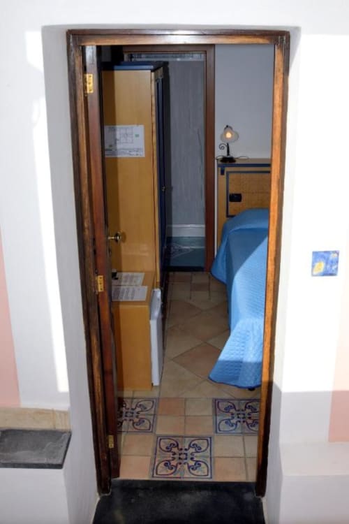 Piccola camera doppia all'Hotel Principe di Rinella a Rinella, Italia, con pavimento piastrellato, biancheria blu, scrivania con lampada e