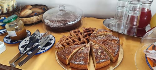 Colazione presso l'Hotel Principe di Rinella con torta affettata, waffle, pasticcini, marmellata e bevande su tavolo giallo