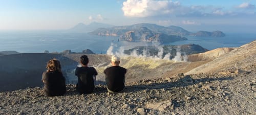 Tre ospiti ammirando le isole vulcaniche di Lipari e il cratere fumante dal belvedere del monte Rinella