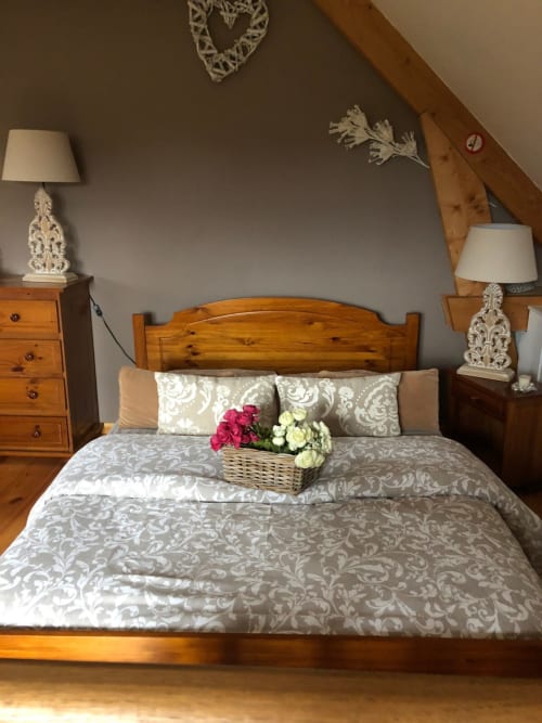 Chambre charmante du gite Le Clos Mahiel avec lit en bois, parure de draps lin, coussins décor, fleurs fraîches et lampes de chevet raffinées