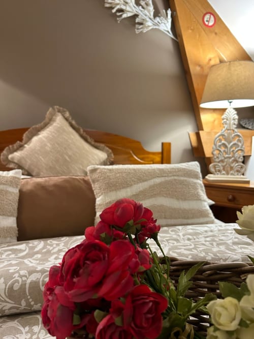 Chambre élégante du gite Le Clos Mahiel avec décoration, coussins décor, mobilier bois et éclairage chaleureux