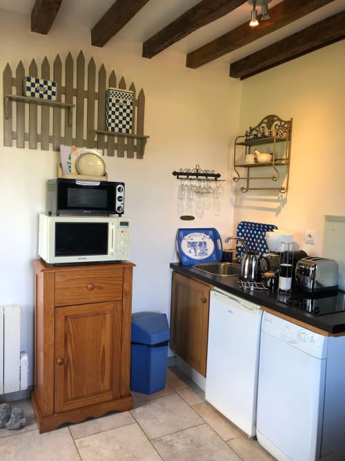 Coin cuisine du Clos Mahiel avec poutres apparentes, micro-ondes, équipements de repas et décor à carreaux bleus