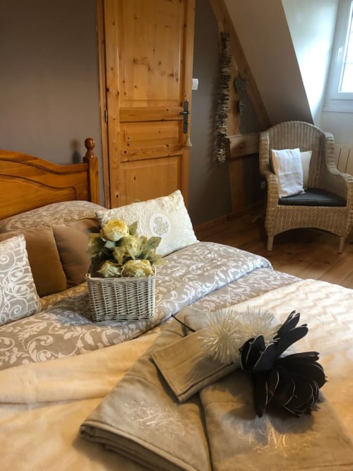 Chambre double, fauteuil en osier et roses en panier au gite Le Clos Mahiel, France