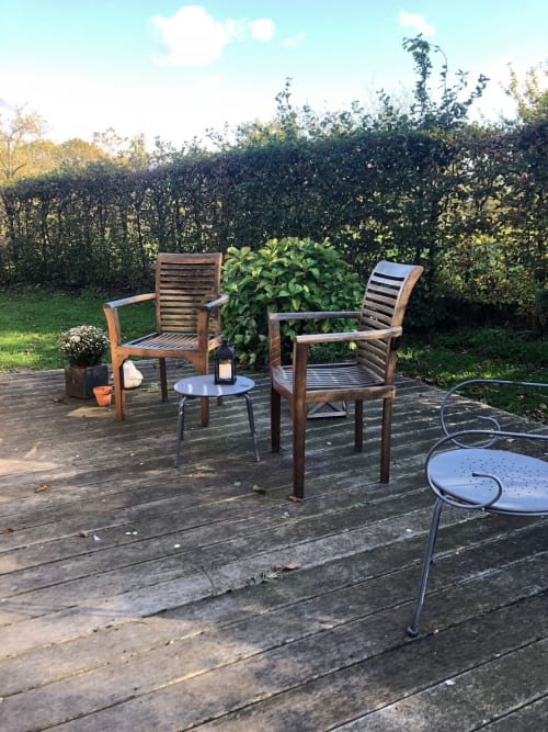 Coin de détente en bois avec chaises et petite table au gite Le Clos Mahiel, entouré de haies vertes et de pelouse