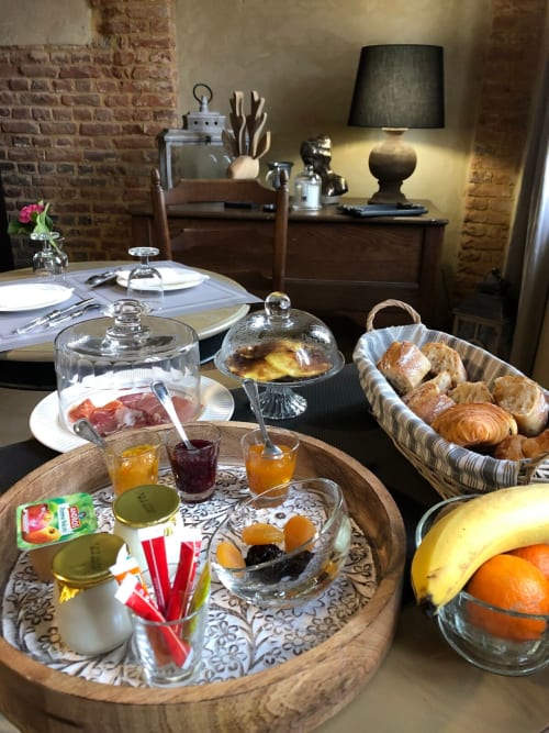 Petits-déjeuners raffinés au Clos Mahiel avec viennoiseries, charcuterie, fromages, fruits frais et boissons chaudes selon le moment dans une salle authentique aux murs de briques 