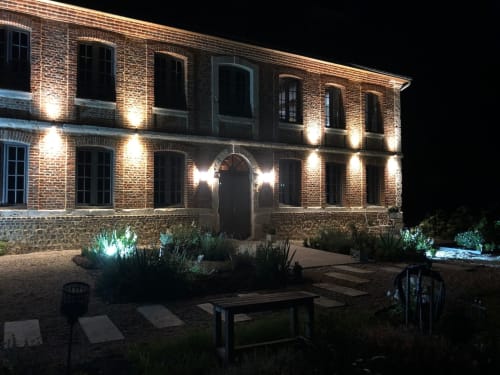 Façade illuminée en briques du Clos Mahiel la nuit, avec espace de détente en jardin à Saint-Romain-de-Colbosc. France. 