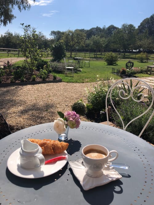 Petit-déjeuner avec croissant et café sur la terrasse du jardin du Clos Mahiel, Saint-Romain-de-Colbosc, avec vues champêtres