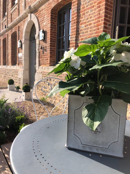 Mobilier de patio blanc et fleurs en pots à fleurs blanches sur la terrasse de la maison d'hôtes en brique au Clos Mahiel,