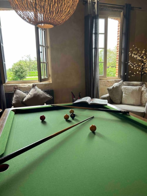 Salle de billard au salon du Clos Mahiel, lampadaire en rotin et vue sur le jardin aux chambres d'hôtes du Clos Mahiel en Normandie