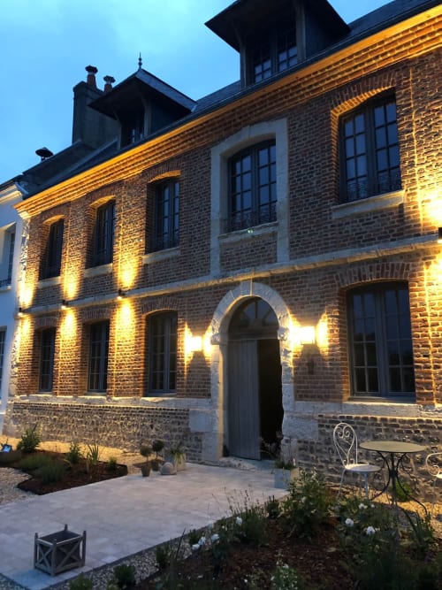 Façade de l'hôtel Le Clos Mahiel au crépuscule, éclairage doré, briques, entrée voûtée et coin détente jardin