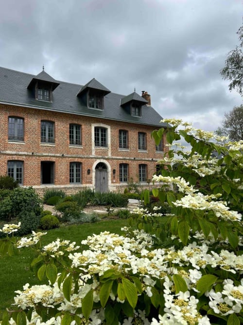 L'hôtel Le Clos Mahiel à Saint-Romain-de-Colbosc, façade en brique, toit mansardé et arbustes fleuris blancs