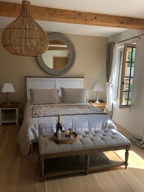 Chambre spacieuse au Clos Mahiel avec lit queen-size, suspension tissée, miroir orné et grandes fenêtres donnant sur les jardins