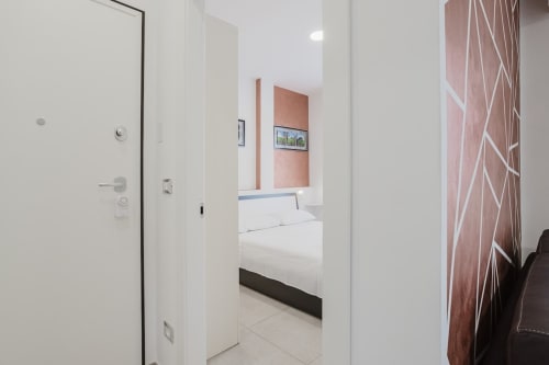 Moderner Schlafzimmereingang in Residenza la Pietra, Pietra Ligure mit weißen Wänden, Meerblickkunstwerken und zeitgenössischen Möbeln