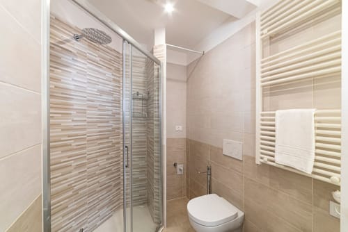 Modernes Badezimmer in Residenza la Pietra mit gestreifter Fliesendouche, Toilette, beheiztem Handtuchhalter und Chromarmaturen