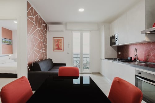 Modernes Studio in Residenza la Pietra mit Küche, schwarzem Sofa, roten Akzenten, geometrischer Wandkunst und Meerblick