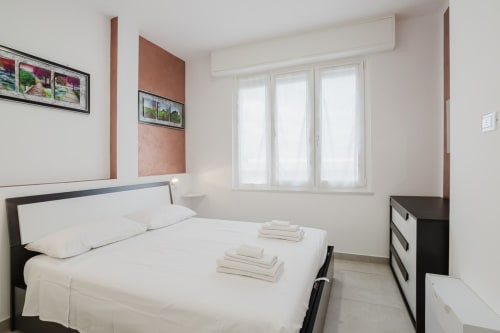 Modernes Schlafzimmer in der Residenza la Pietra in Pietra Ligure mit weißer Bettwäsche, schwarzen Möbeln und Meerblick