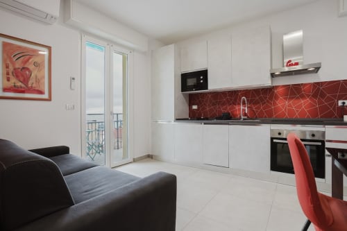 Moderne Küche und Wohnbereich der Wohnung Pietra-Rossa in der Residenza la Pietra, Pietra Ligure, mit roten geometrischen Elementen