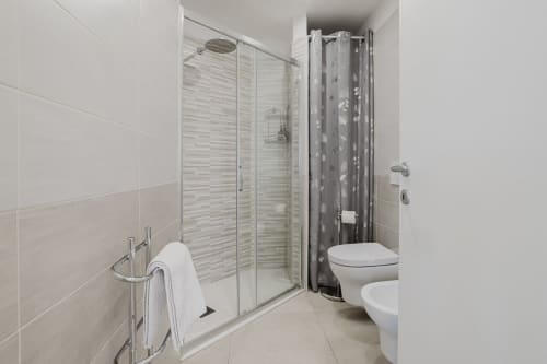 Modernes Badezimmer mit Glasdusche, Toilette, Bidet und weißen Kacheln in der Residenza la Pietra, Pietra Ligure