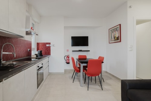 Moderner rot-weißer Küchen-Essbereich in der Residenza la Pietra, Pietra Ligure, mit TV und Meerblick