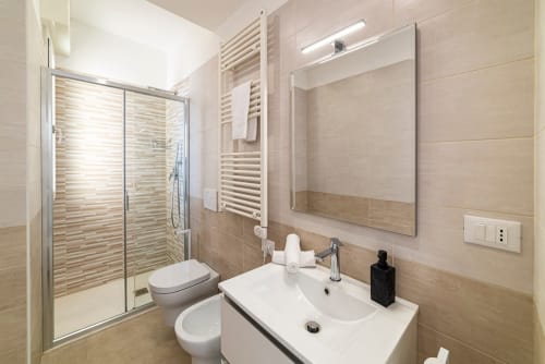 Modernes Badezimmer in der Residenza la Pietra in Pietra Ligure mit Dusche, Toilette, Doppelwaschbecken und Handtuchheizung