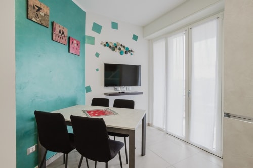 Moderner Essbereich im Residenza la Pietra, Pietra Ligure mit türkisblauer Akzentwand, schwarzen Stühlen und weißem Tisch