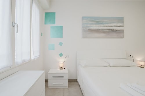 Helles, minimalistisches Schlafzimmer in der Residenza la Pietra mit Einzelbetten, türkiser Wandkunst, Meerblickgemälde und modernem Design