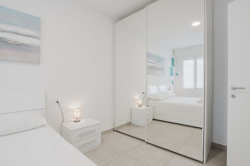 Modernes Schlafzimmer in der Residenza la Pietra mit Spiegelschrank, weißen Möbeln und Meereskunstwerk