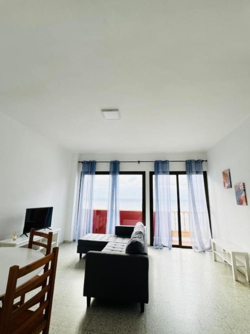 Sala moderna de Rocamar con sofá negro, ventanales y vistas al mar en Santa Cruz de la Palma