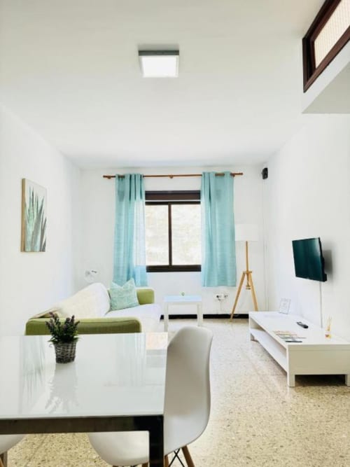 Apartamento estudio moderno en Rocamar, Santa Cruz de la Palma con cortinas turquesas, muebles blancos y acentos verdes
