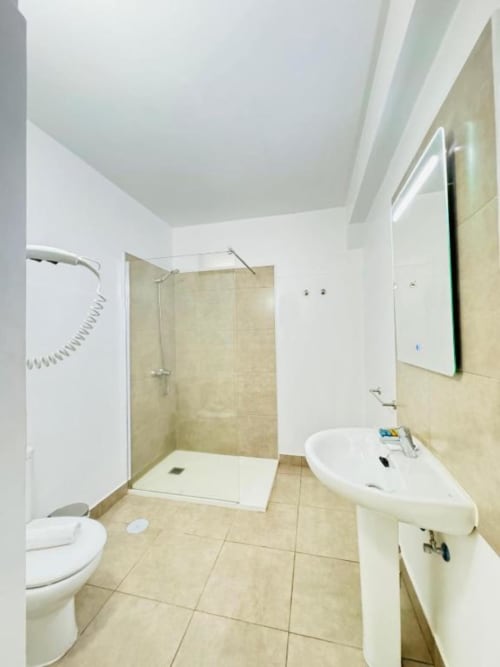 Baño moderno en Apartamentos Rocamar con ducha a ras de suelo, lavamanos de pedestal e inodoro en Santa Cruz de la Palma