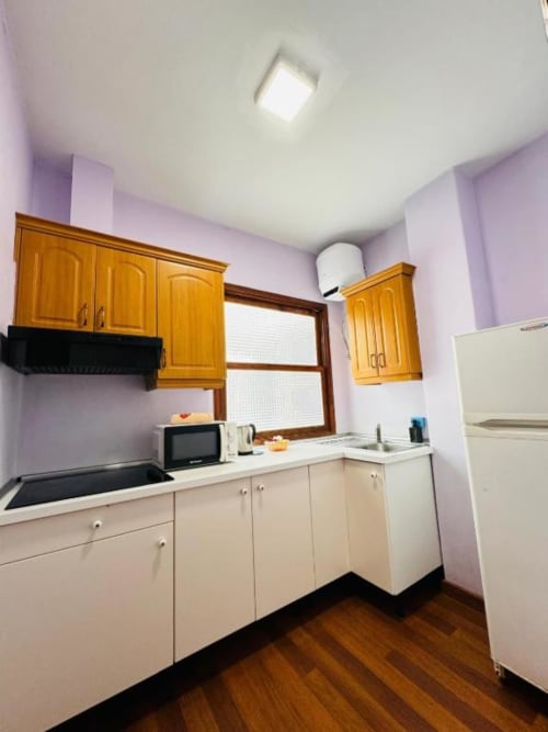 Cocina moderna en Apartamentos Rocamar con muebles de madera, encimeras blancas y paredes violetas en Santa Cruz de la Palma