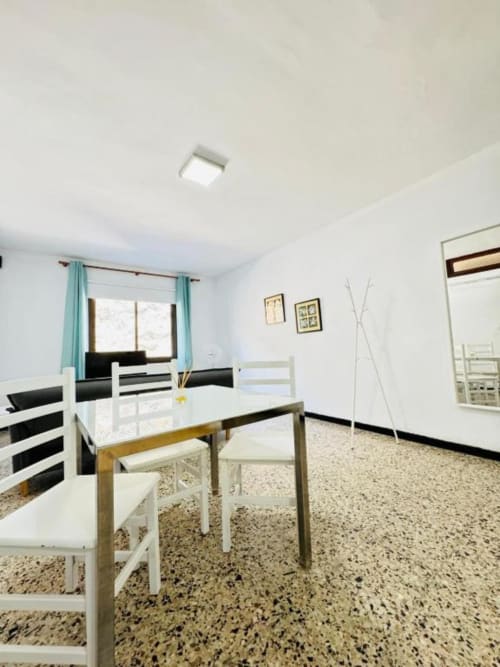Comedor moderno en Rocamar Santa Cruz de la Palma con sillas blancas, mesa de madera y piso de terrazo