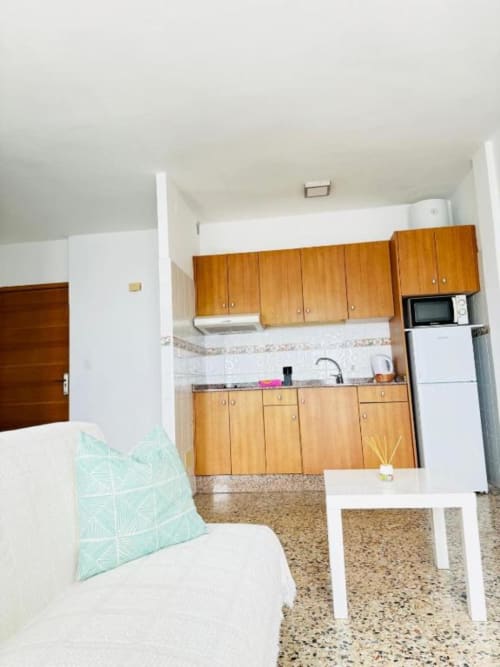 Cocina y área de estar tipo estudio en Apartamentos Rocamar, Santa Cruz de la Palma con muebles de madera y encimeras de granito