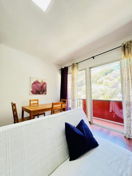 Comedor luminoso en Apartamentos Rocamar con mesa de madera, paredes de azulejos blancos y terraza con vistas a Santa Cruz de la