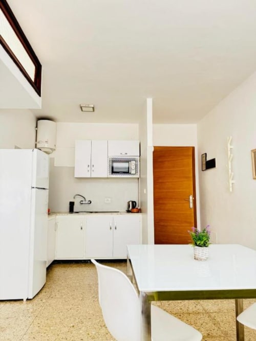 Cocina moderna con armarios blancos, refrigerador y microondas en Apartamentos Rocamar, Santa Cruz de la Palma