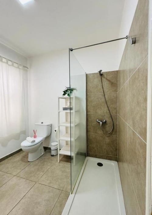 Baño moderno en Apartamentos Rocamar con ducha tipo walk-in, inodoro y piso de azulejos blancos