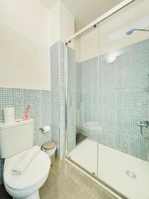 Baño moderno con azulejos verdes, ducha, inodoro y lavamanos en Apartamentos Rocamar, Santa Cruz de la Palma