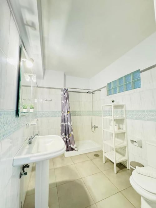 Baño moderno en Apartamentos Rocamar con ducha a ras de suelo, lavabo pedestal y suelos de azulejo en Santa Cruz de la Palma